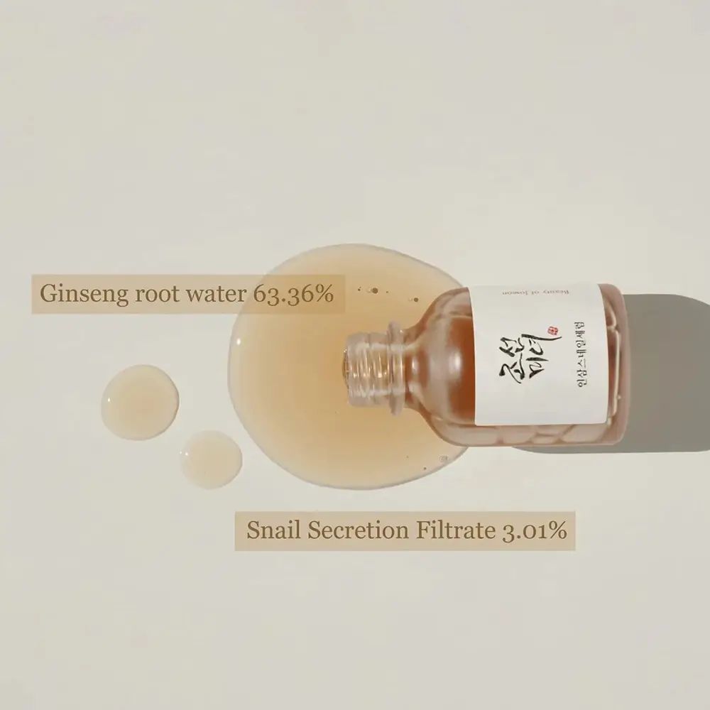 Flacone trasparente con siero e gocce. Etichetta con scritta coreana. Ginseng root water 63.36%. Snail Secretion Filtrate 3.01%.