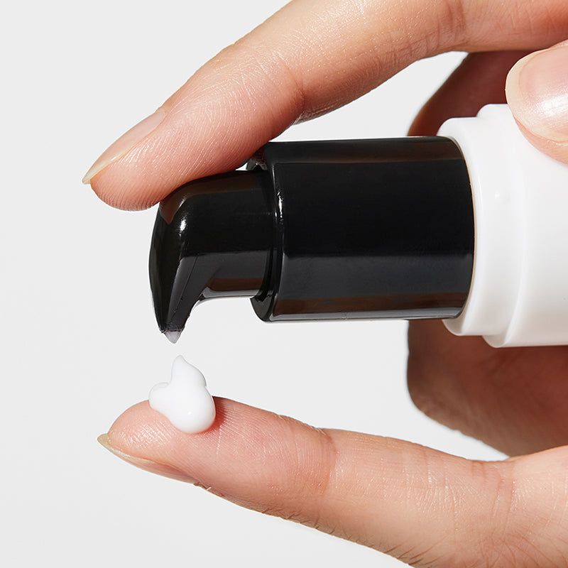 Primo piano di una mano che eroga crema da un erogatore su un dito. Crema bianca.