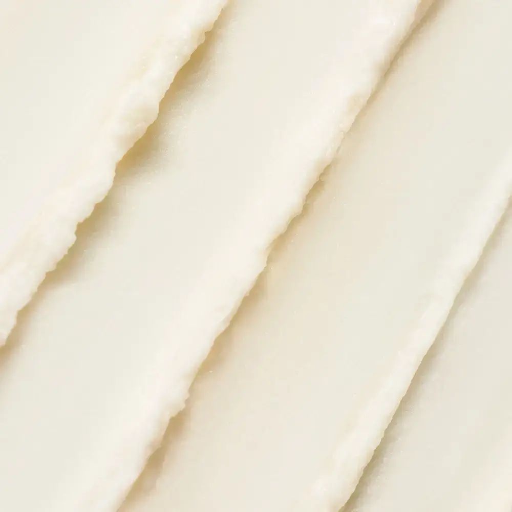 Primo piano della texture cremosa e bianca di una crema solare. Strisce irregolari visibili.