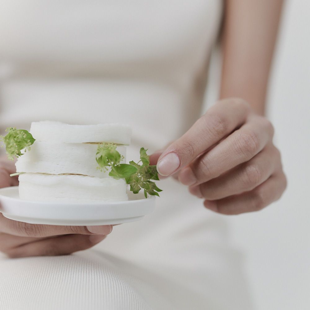 Mani che tengono tre dischetti Celimax Ji Woo Gae CICA BHA Blemish Toner con rametti verdi.