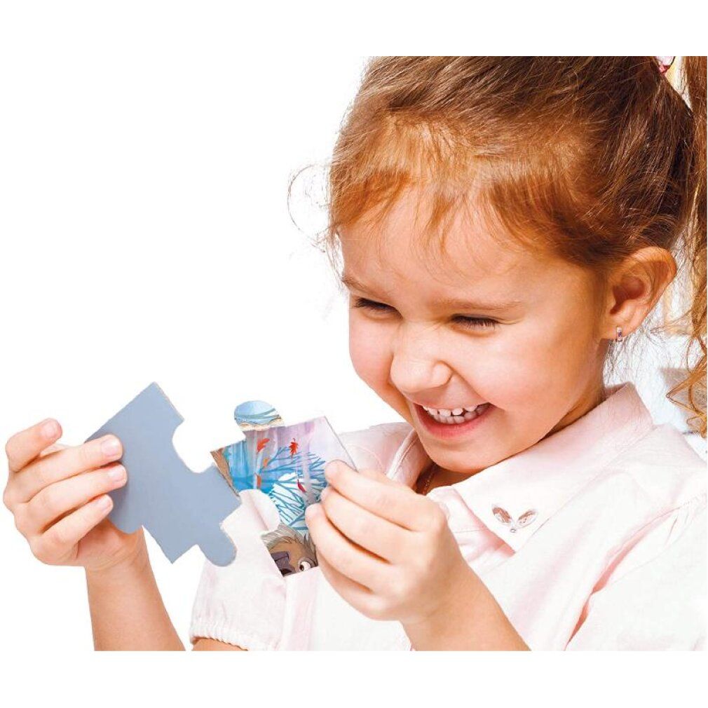 Bambina tiene in mano un pezzo di puzzle Frozen. Il pezzo è grigio e di forma irregolare.
