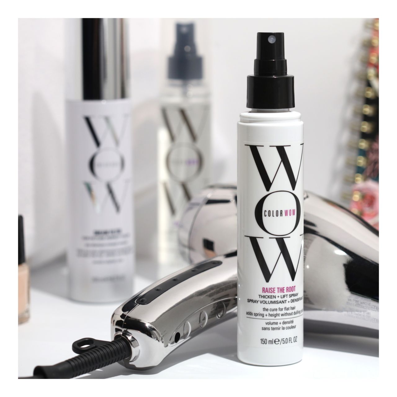 Flacone spray per capelli con logo "WOW" e nome del prodotto. Altri flaconi e asciugacapelli sullo sfondo.