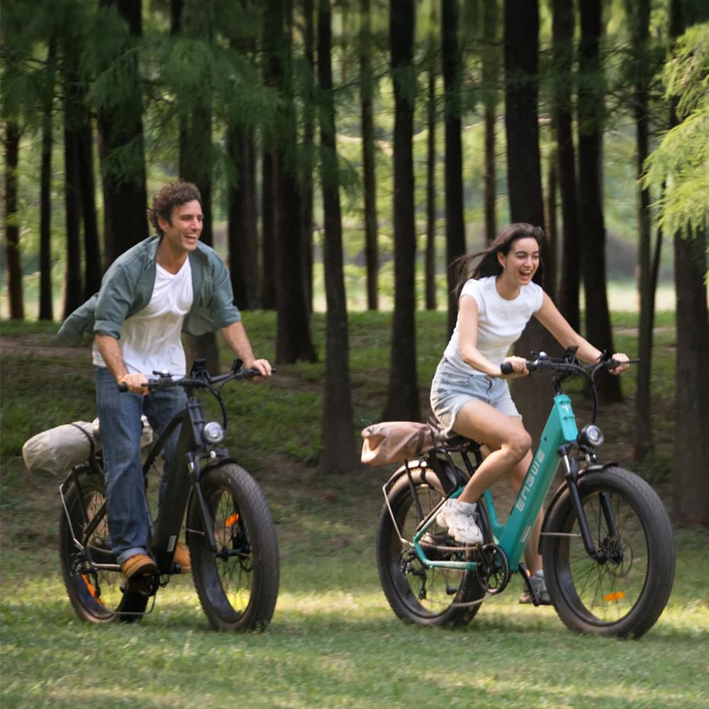 Due persone in sella a e-MTB su un prato. Entrambe le bici hanno pneumatici larghi.