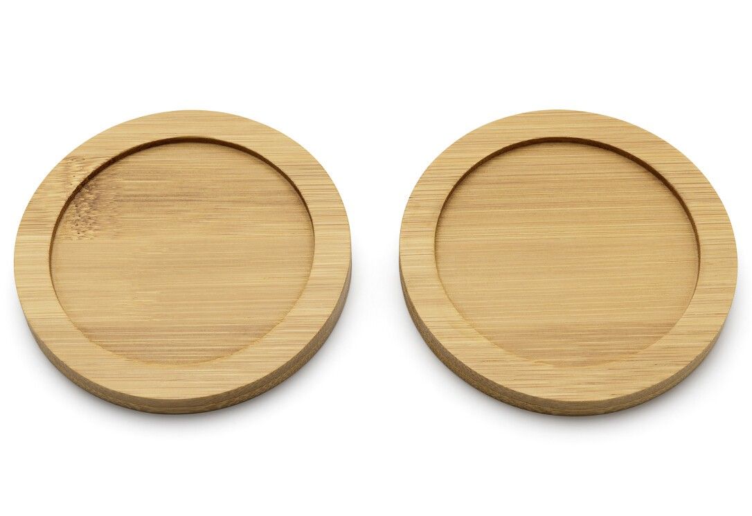 Due sottobicchieri rotondi in legno chiaro. I sottobicchieri hanno un bordo rialzato. Lo sfondo è bianco.