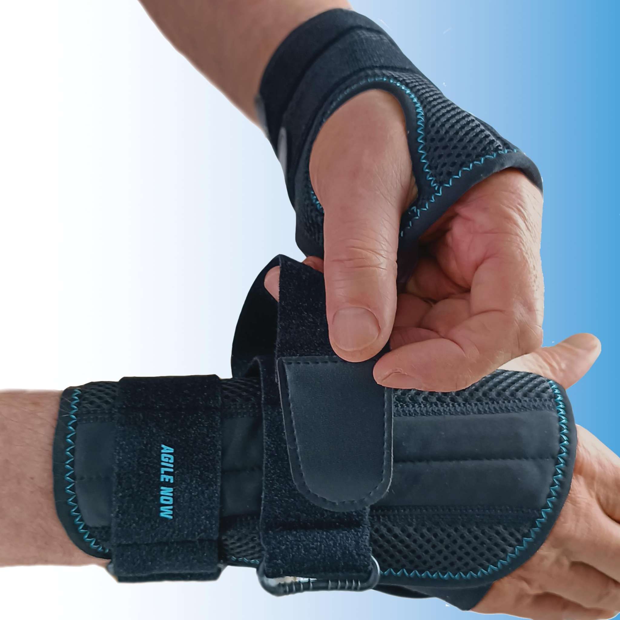 Persona che tiene un tutore per polso. Nero, con velcro. Testo: AGILE NOW. Maglia. Cucitura blu. Tutore per polso.