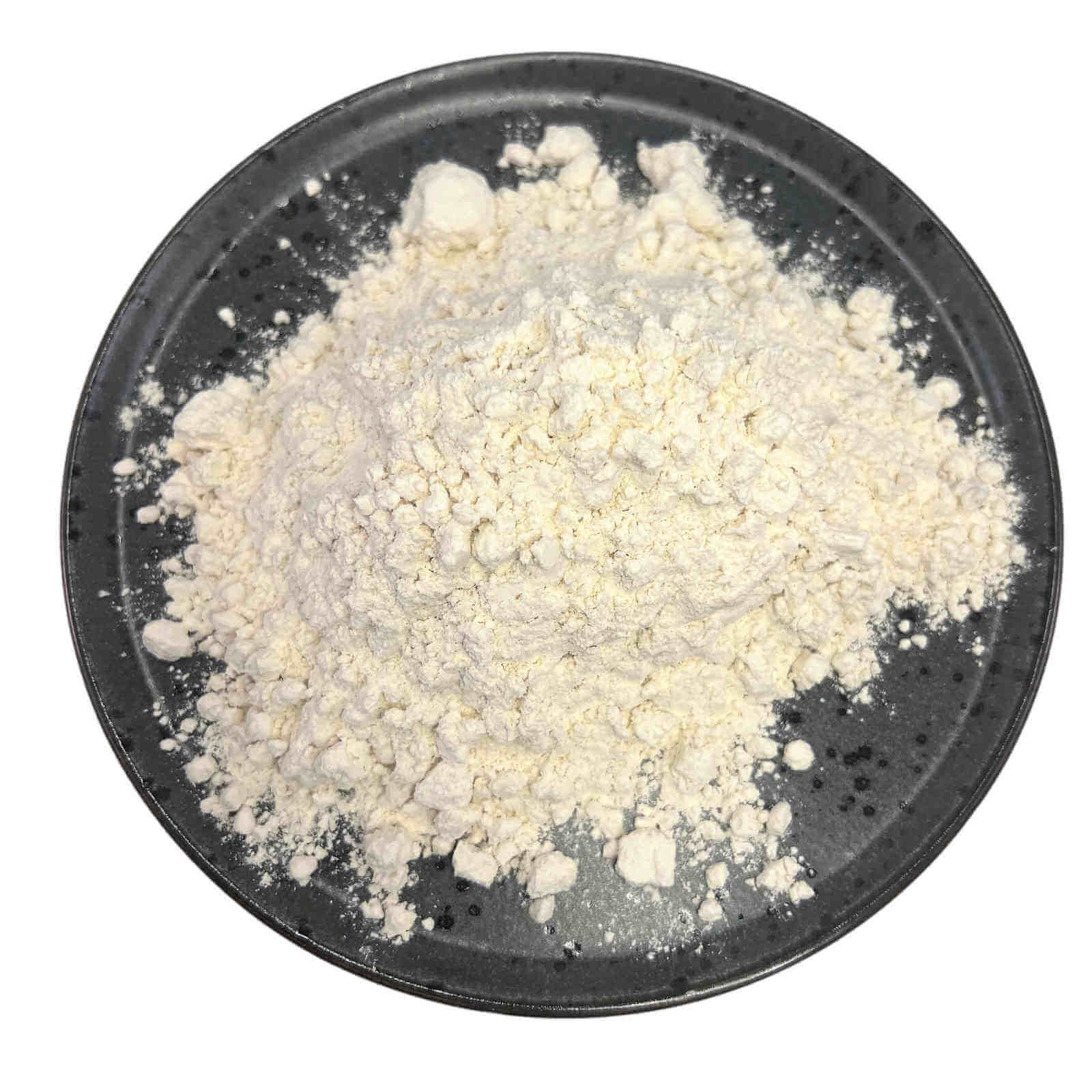 Farina su un piatto scuro. La farina è chiara e fine. Il piatto è rotondo e ha un bordo rialzato.