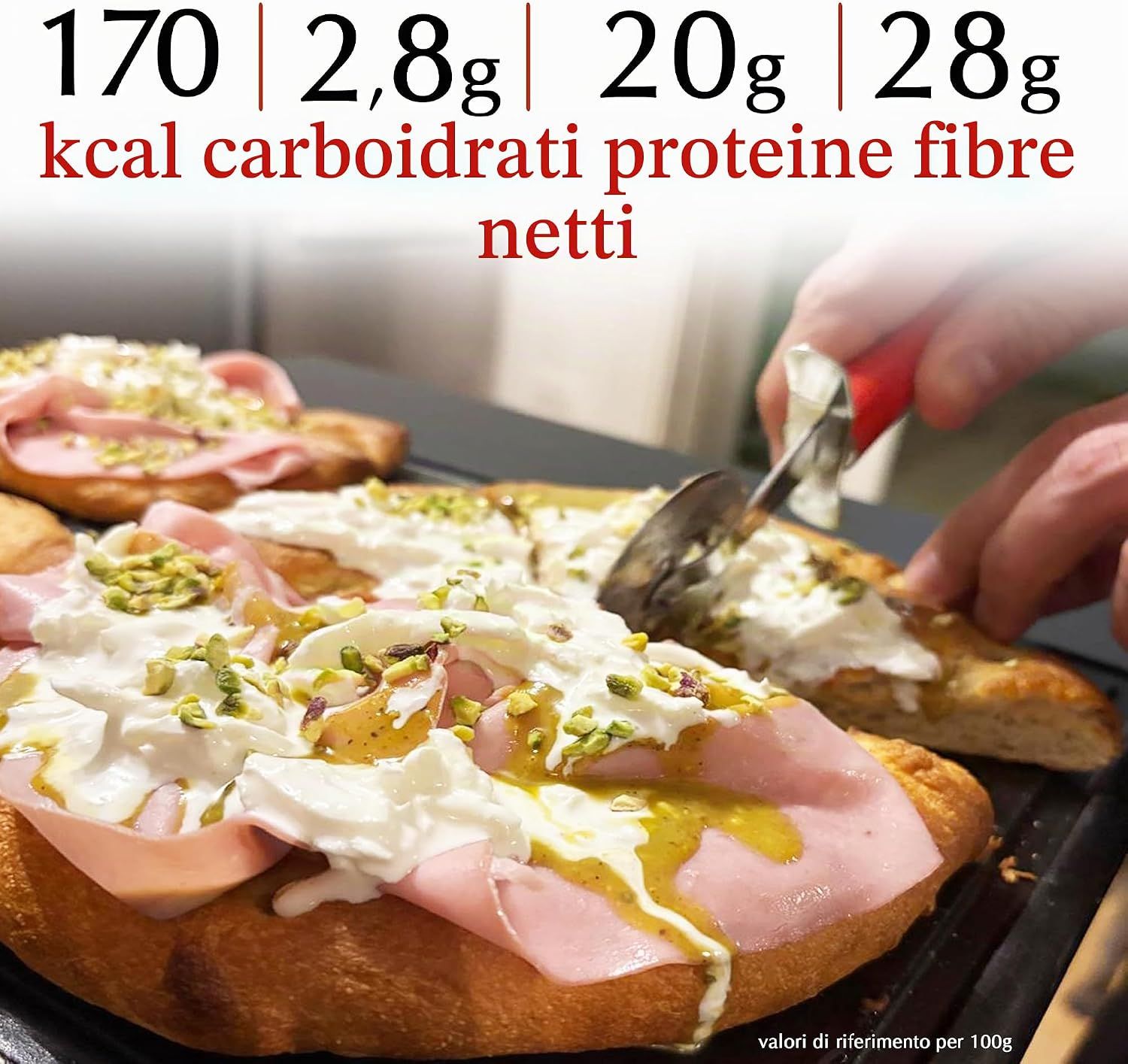 Una persona che taglia una focaccia keto con prosciutto, formaggio e pistacchi su una griglia.