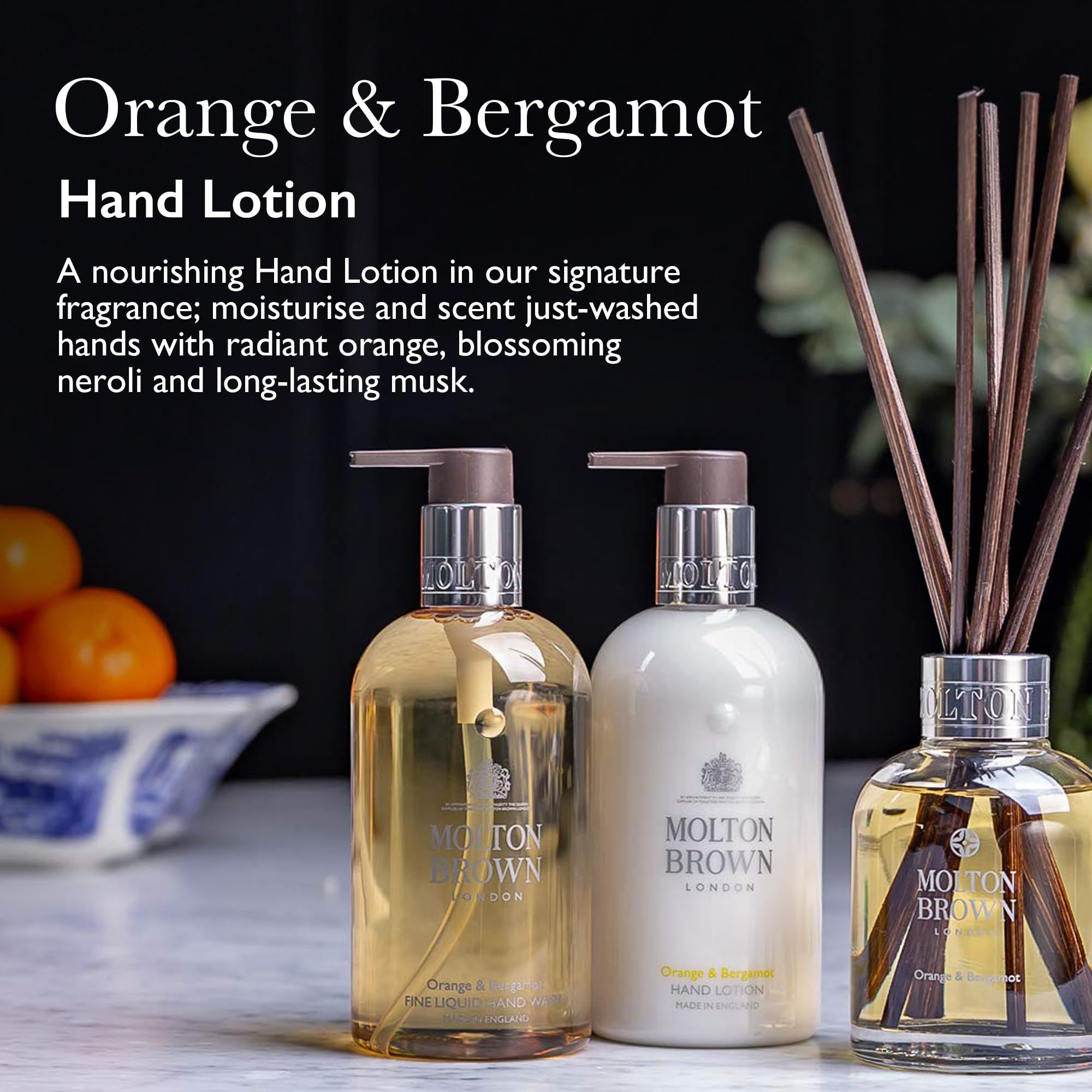 Due flaconi di lozione per le mani e un diffusore. Scritta: Molton Brown London, Orange & Bergamot. Sfondo: frutta e decorazioni.