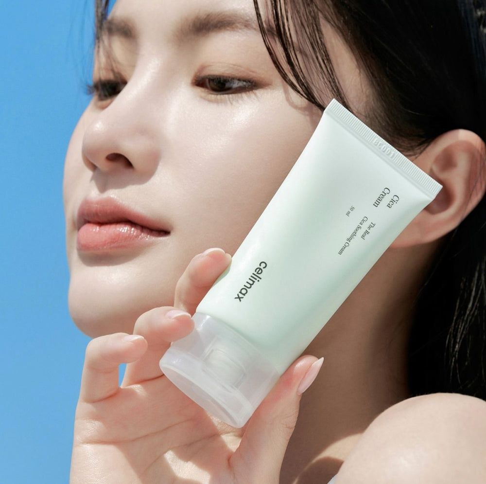 Donna che tiene un tubo di Celimax Cica Creme davanti a un cielo blu.