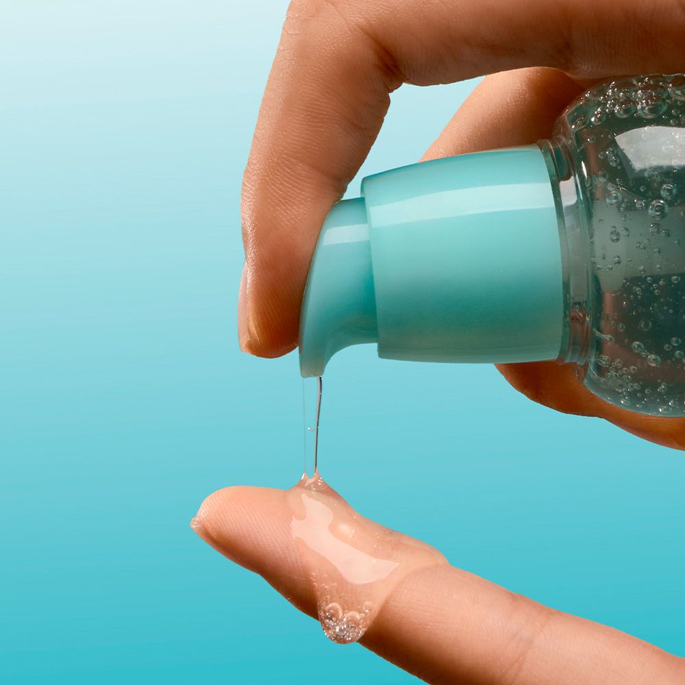Una mano preme un erogatore per erogare un liquido trasparente su un dito.