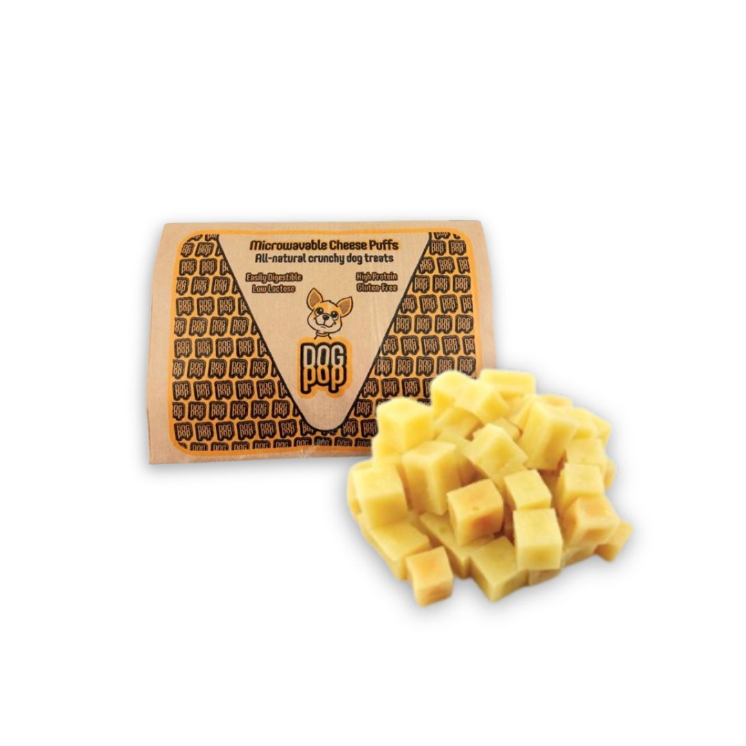 Confezione con soffietti al formaggio per microonde. Cubetti di formaggio gialli accanto. Scritta: Micro-waveable Cheese Puffs, All-natural crunchy dog treats.