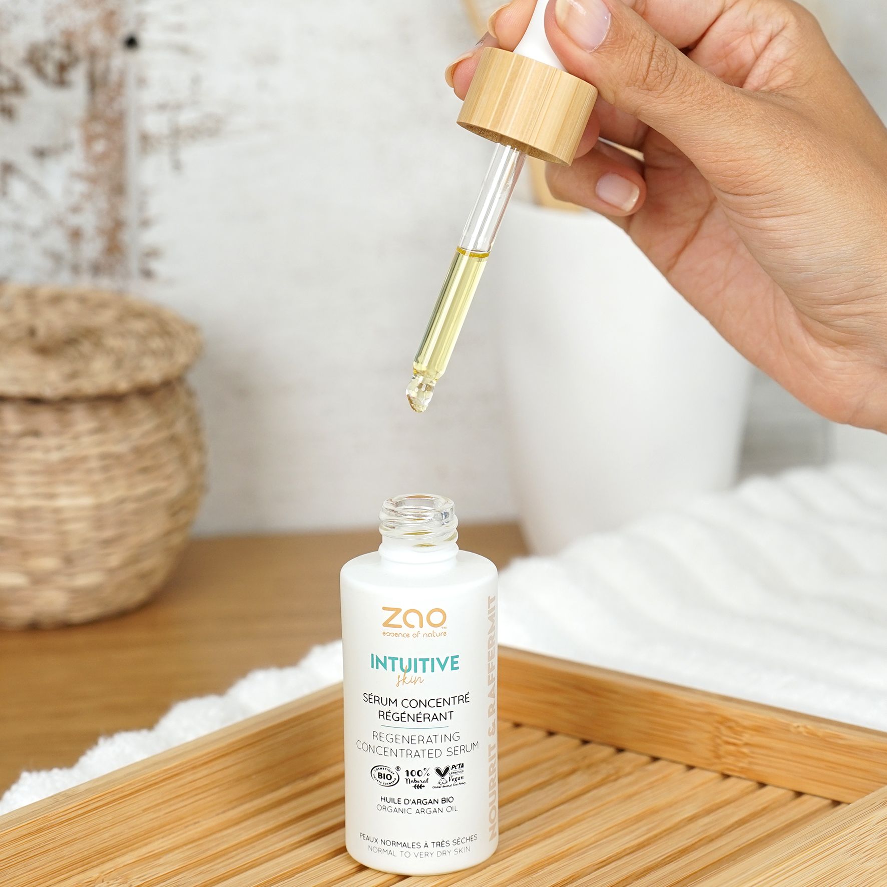 Flacone bianco con pipetta. Goccia di siero. Scritta: ZAO, Intuitive, Sérum concentré régénérant. Su vassoio di legno.