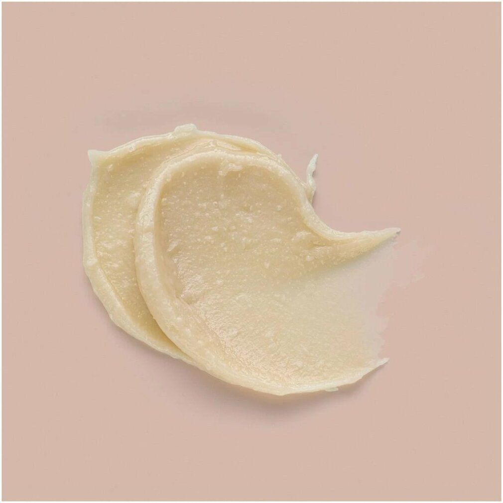 Macchia di cera color crema chiaro su sfondo rosa. La consistenza è visibile.