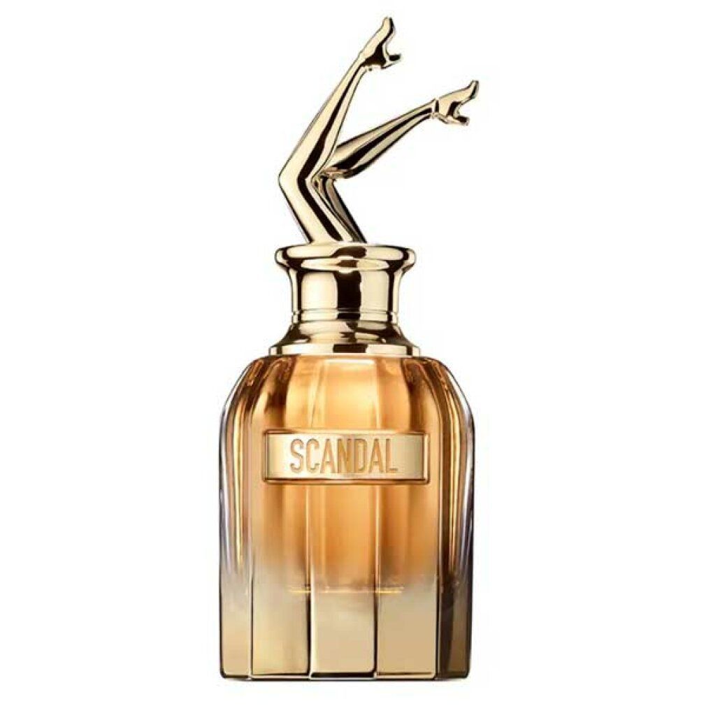 Flacone di profumo con tappo dorato a forma di gambe. Scritta Scandal. Flacone dorato con liquido ambrato.