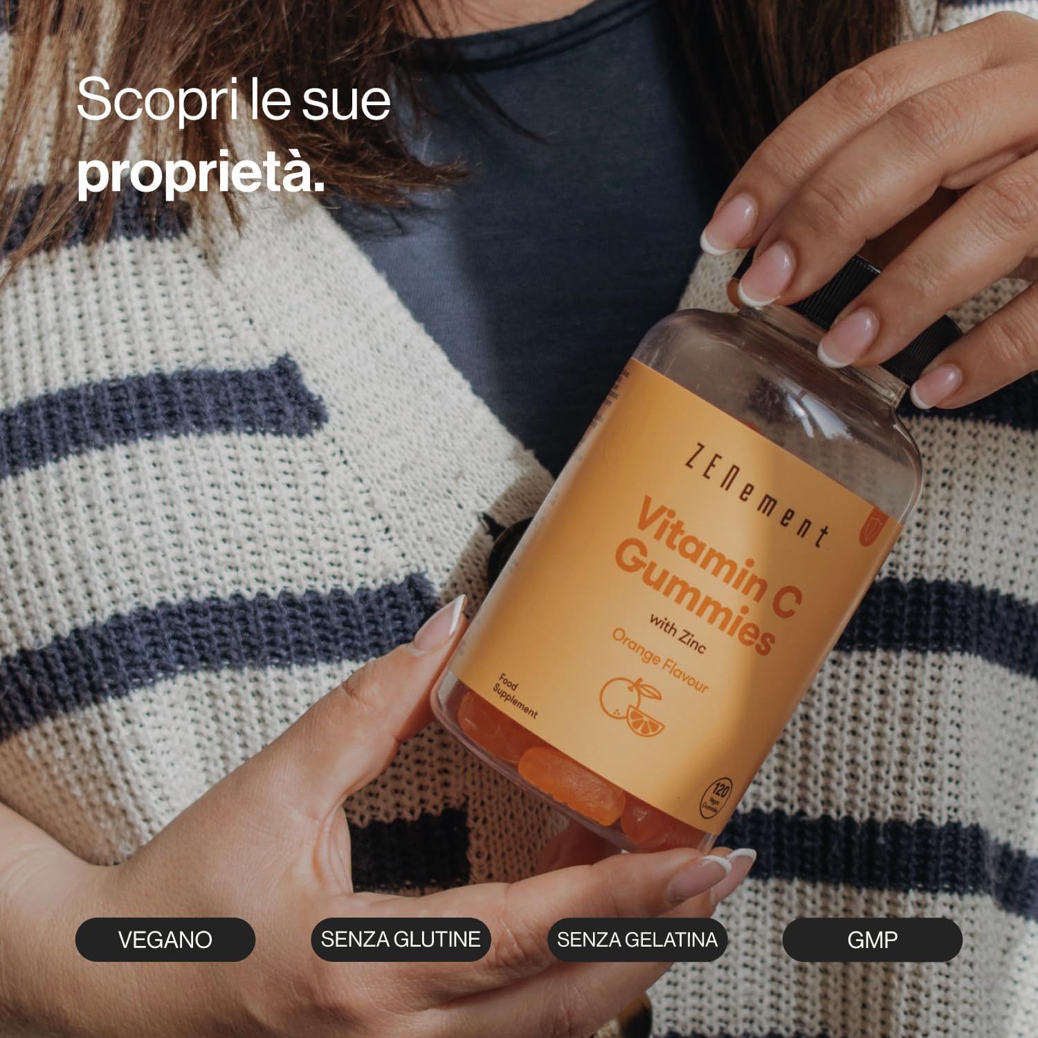 Donna che tiene in mano un flacone di caramelle gommose Zenement Vitamina C. Testo: Vitamin C Gummies with Zinc, Orange Flavor. Vegano, senza glutine, senza gelatina, GMP.