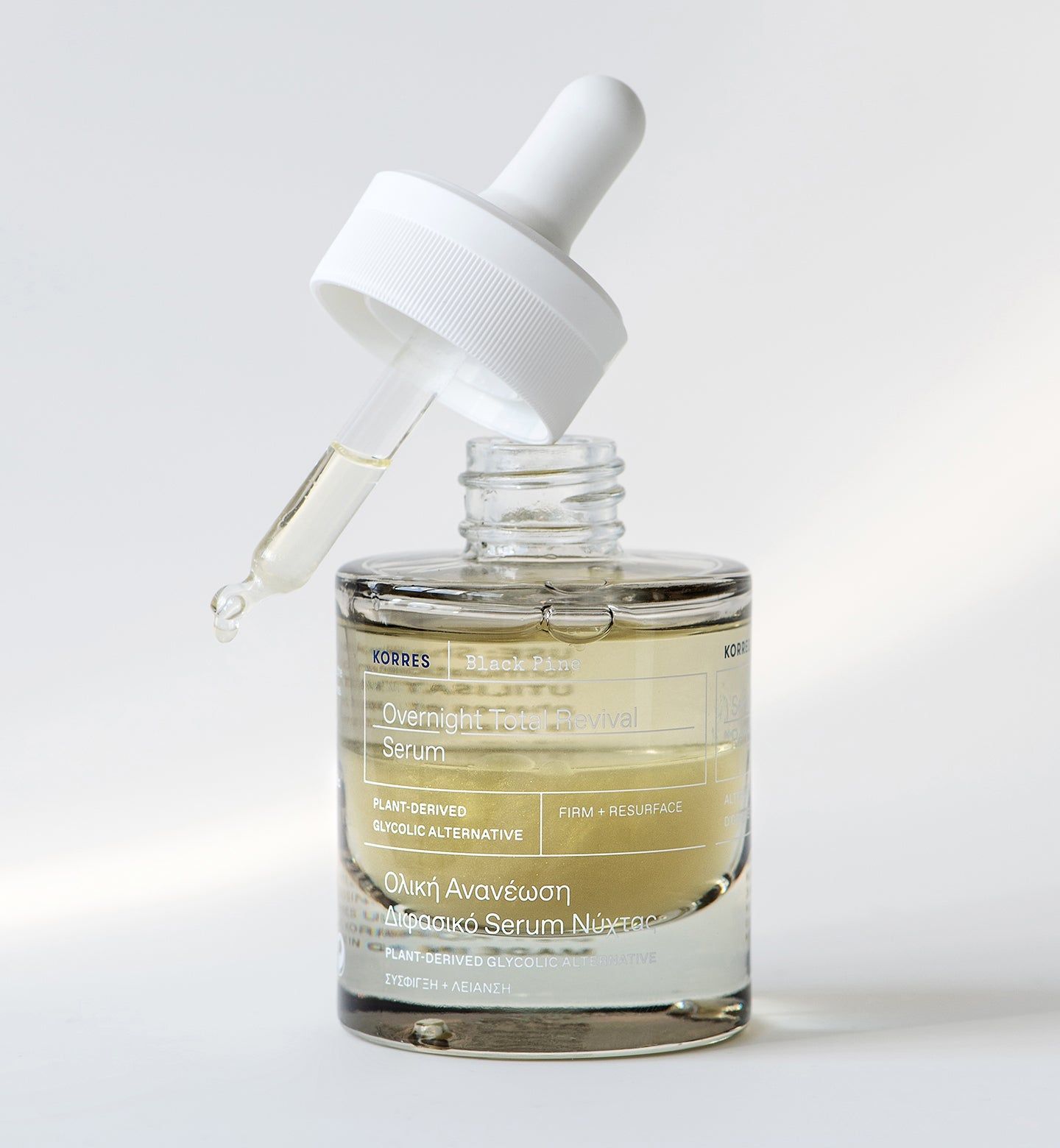 Flacone di vetro con siero e pipetta. Pipetta con goccia di siero. Marchio KORRES visibile. Sfondo bianco.