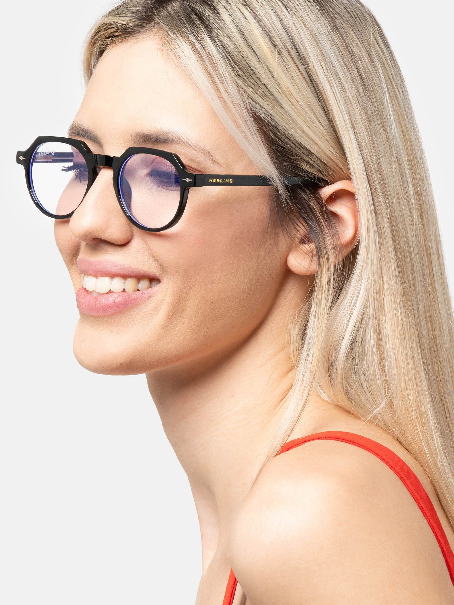 Donna con occhiali neri con lenti rotonde. Il logo Herling è visibile sull'asta. Filtro luce blu.