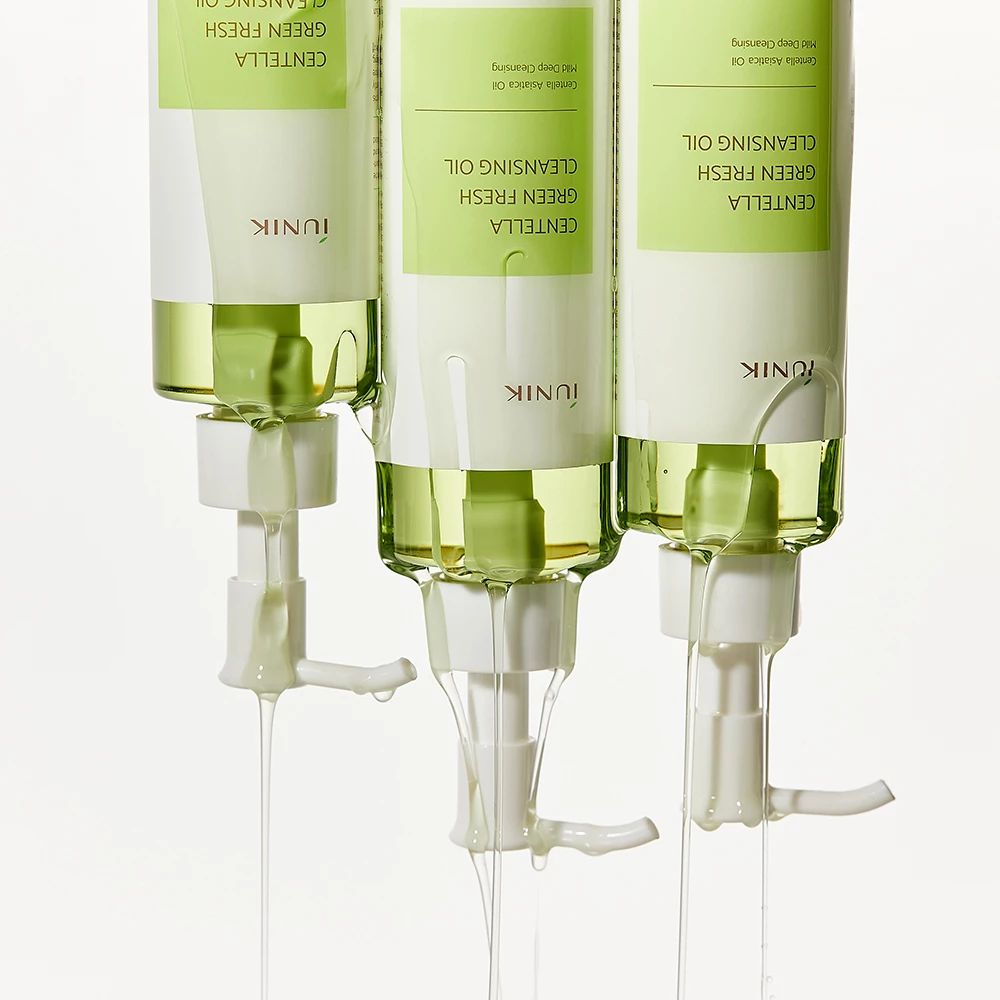 Tre flaconi con erogatori bianchi. Olio verde che fuoriesce dagli erogatori. Scritta: CENTELLA GREEN FRESH CLEANSING OIL, iUNIK.