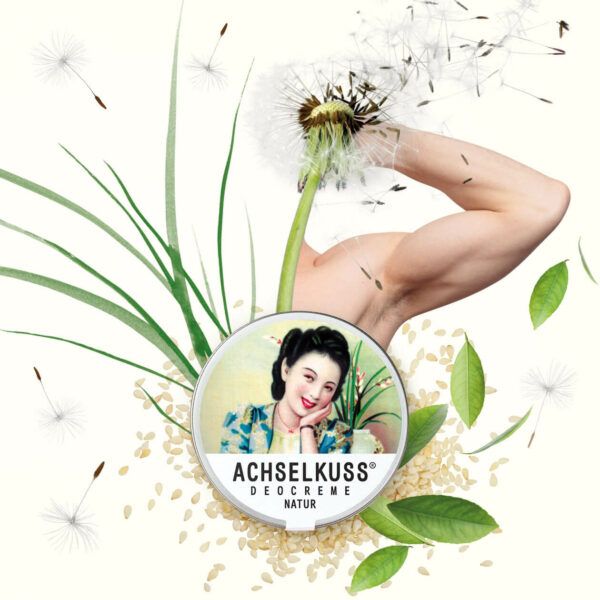 Scatola ACHSELKUSS Deocreme Natur circondata da soffioni e foglie.