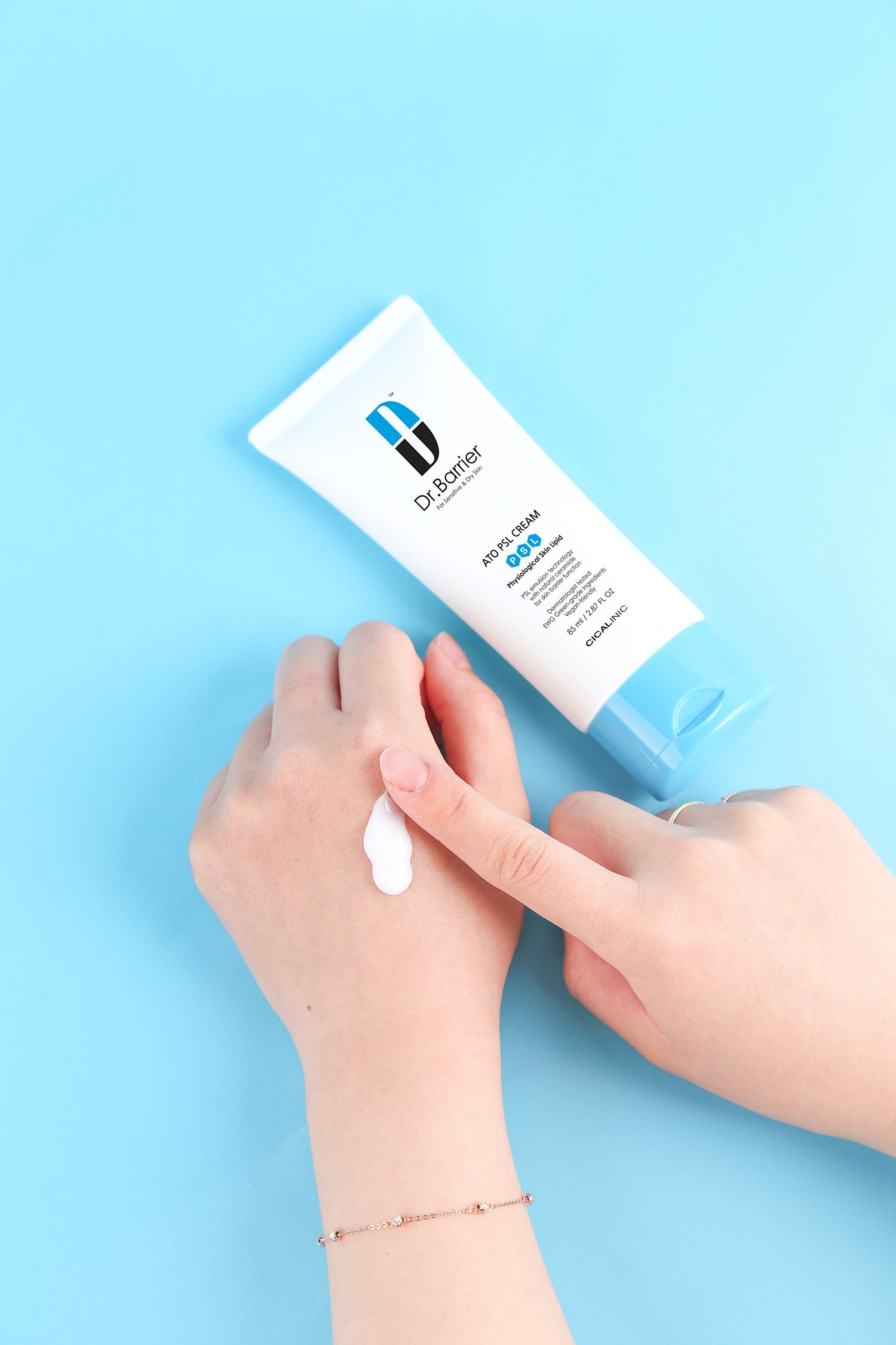Un tubo di Dr.Barrier ATO PSL Cream. Crema applicata sulla mano. Schema colori blu e bianco.