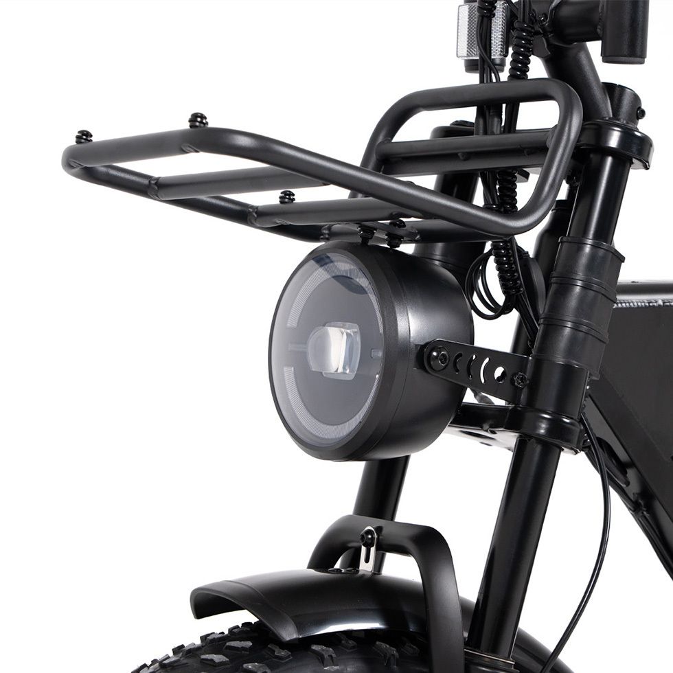 Primo piano del faro nero e del portapacchi di una e-bike. Forma del faro rotonda.