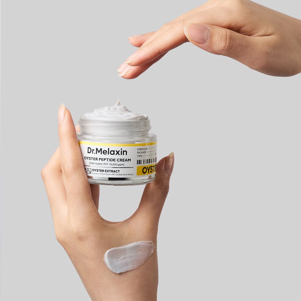 Mano che tiene la crema peptidica di ostrica Dr. Melaxin, con un campione di crema sul palmo.