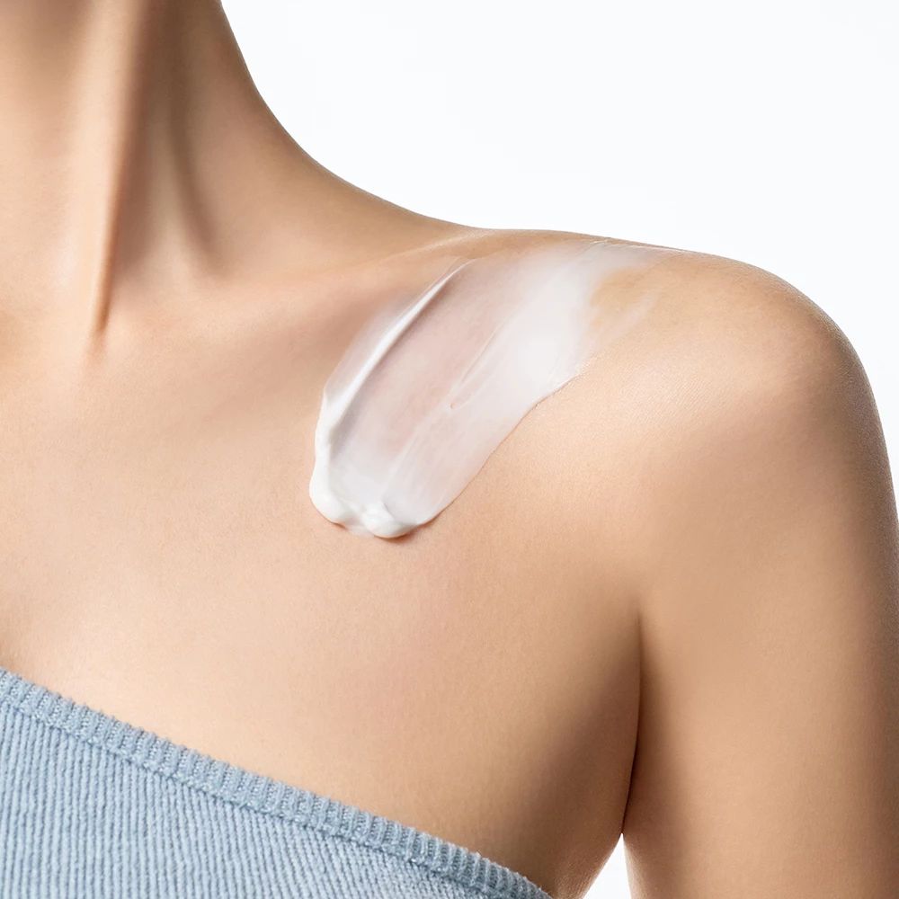 Pelle chiara con crema applicata sulla spalla. Top blu.