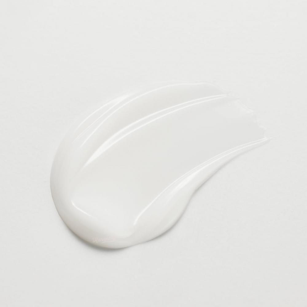 Prodotto per la cura della pelle bianco su sfondo chiaro. Texture cremosa, lucida.
