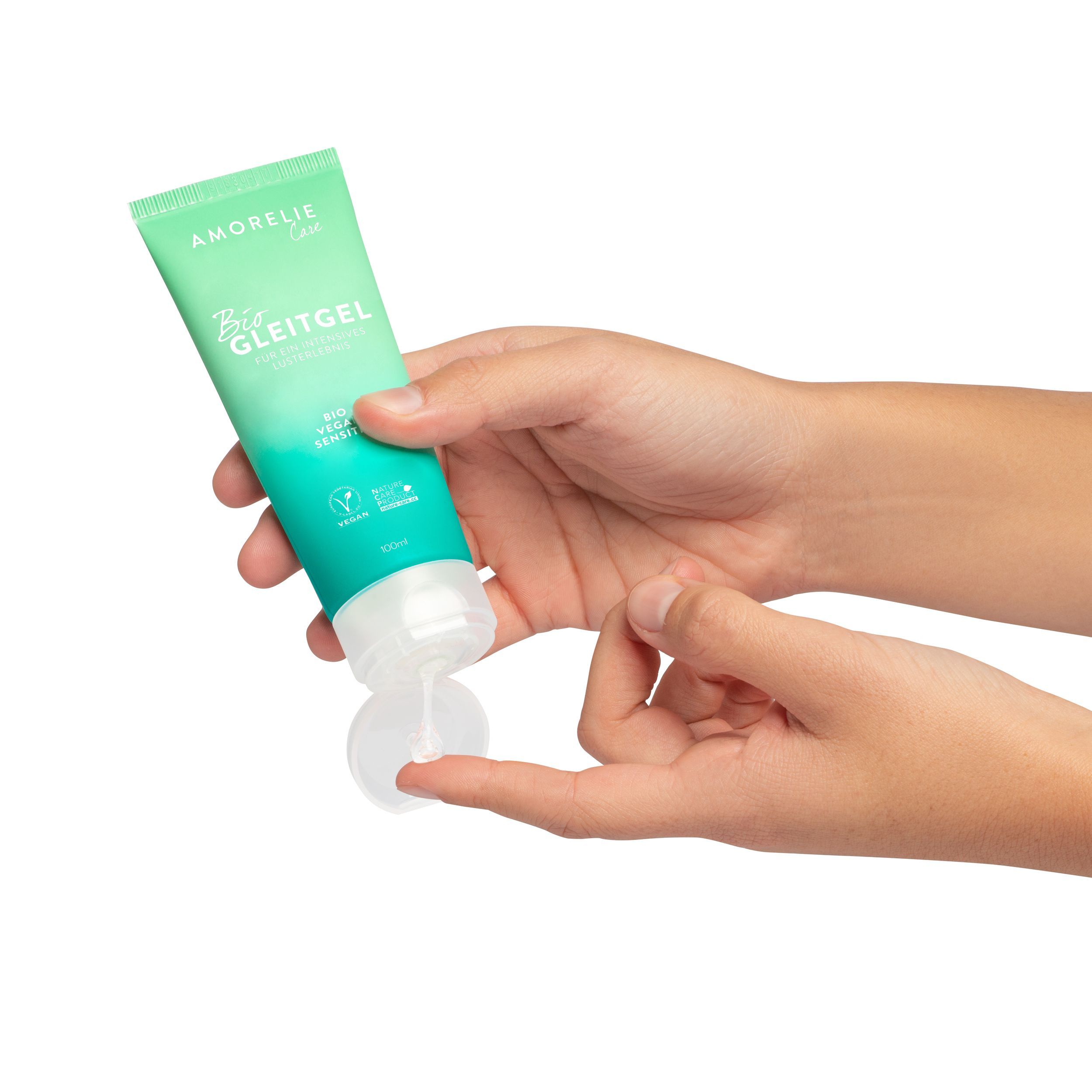 Mani che tengono un tubo verde. Tappo aperto, prodotto visibile. Scritta: AMORELIE Care, Bio Gleitgel, Bio Vegan Sensitiv. Sigillo vegano.