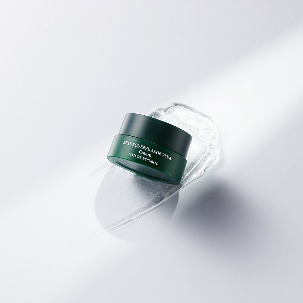 Barattolo verde con testo: Real Squeeze Aloe Vera Cream, Nature Republic. Su sfondo bianco con acqua.