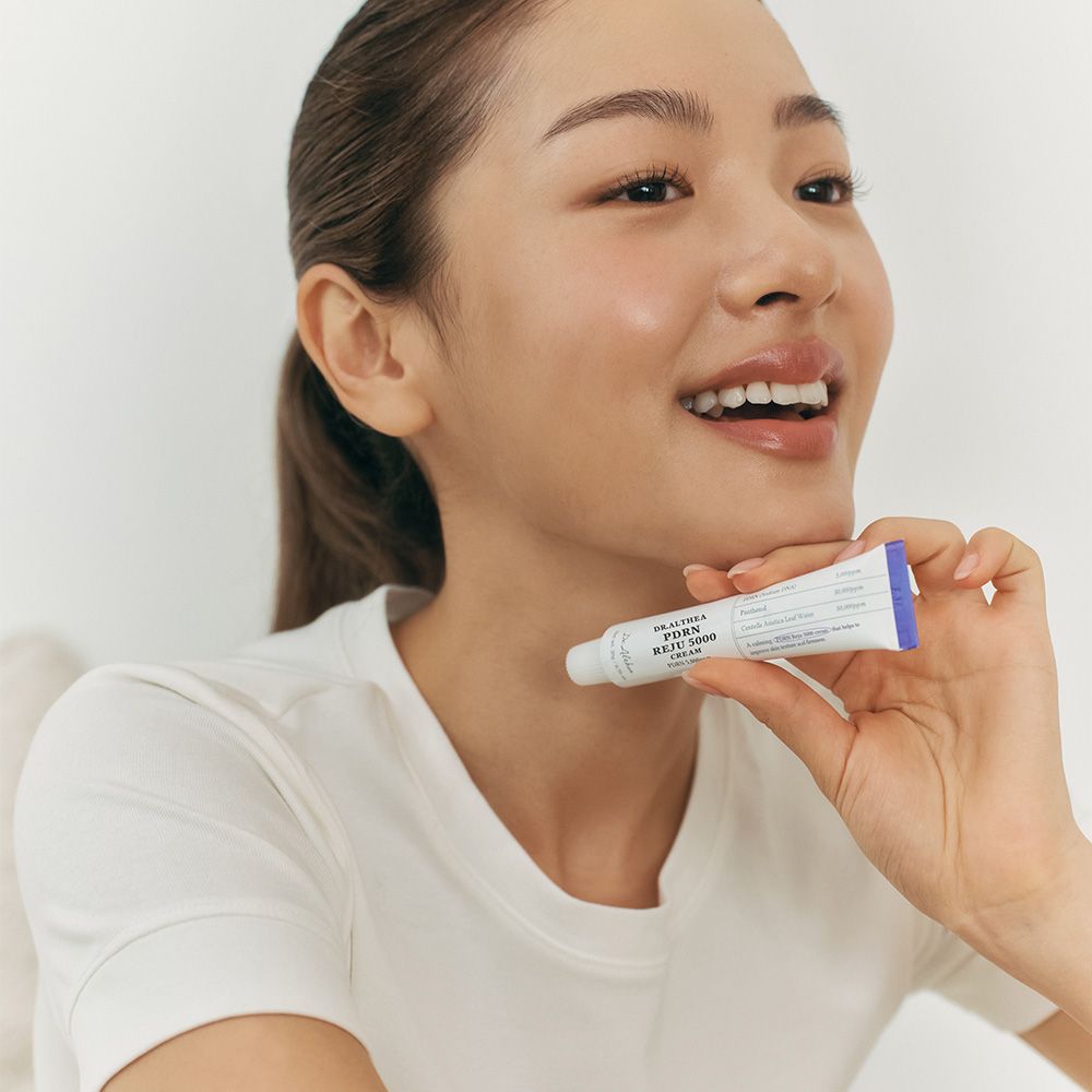 Una donna tiene un tubo di crema Dr.Althea PDRN Reju 5000 vicino al collo.