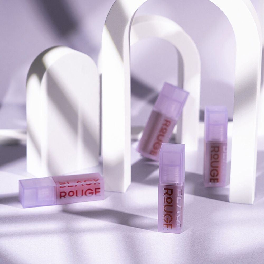 Diversi flaconi di gloss, BLACK ROUGE, in un ambiente decorativo. Tappi e flaconi viola.