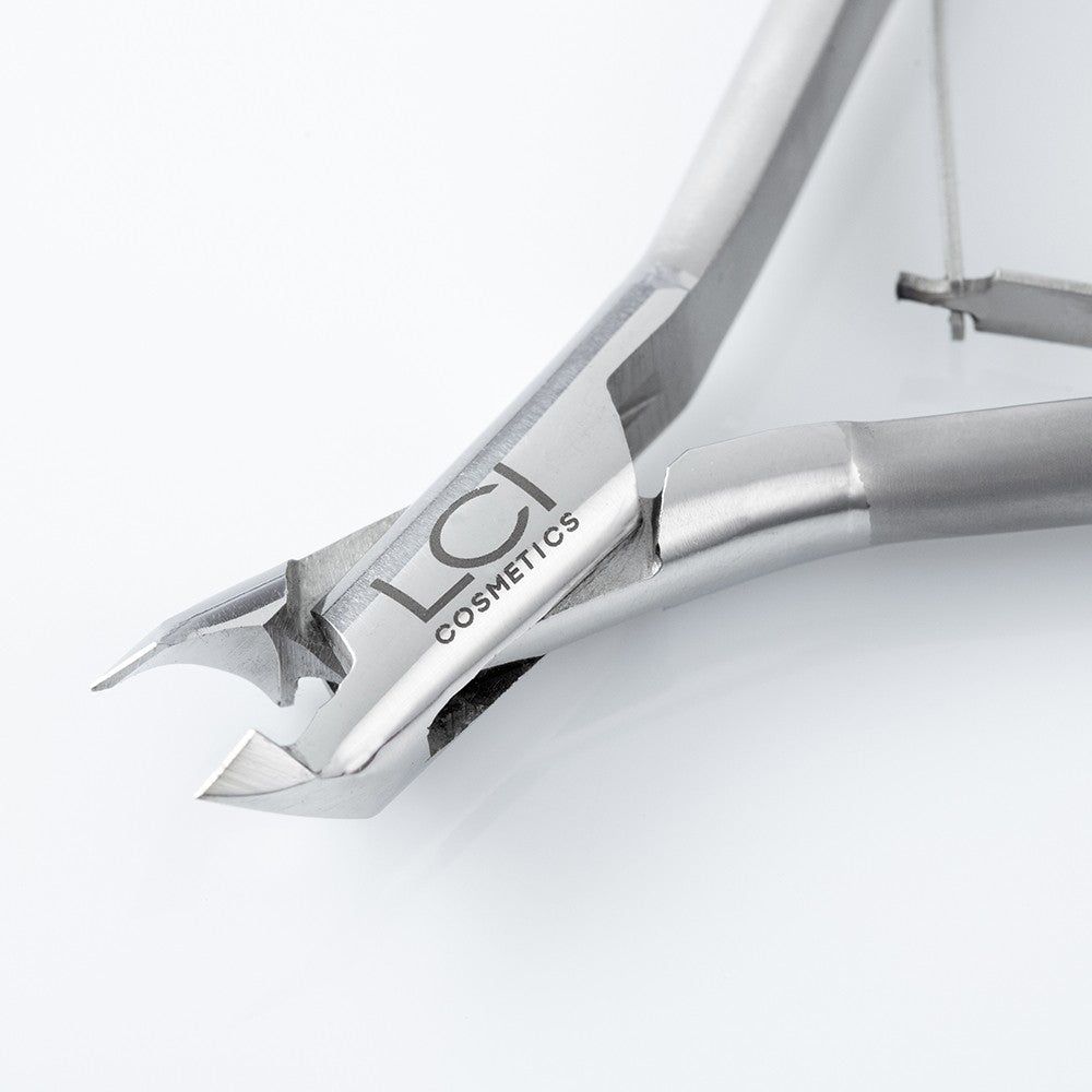 Primo piano della tronchesina per cuticole. Logo LCI Cosmetics visibile. Finitura metallica. Su sfondo chiaro.