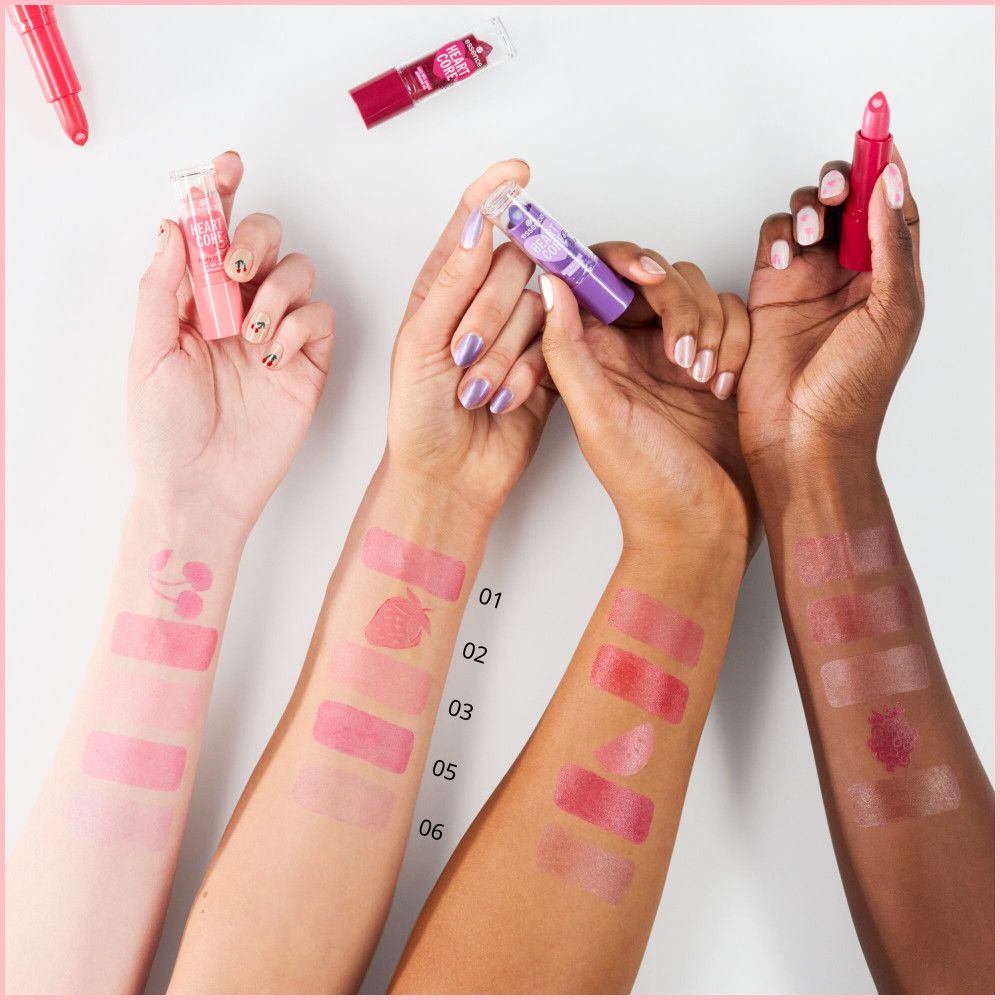 Mani con campioni di balsamo per labbra in diversi colori. Diverse tonalità sono applicate sulle braccia.