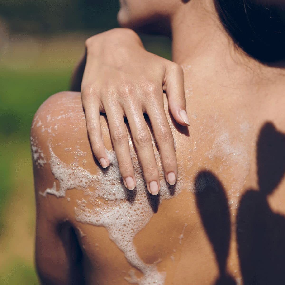 Schiena di una persona coperta di schiuma di sapone. Una mano tocca la spalla.