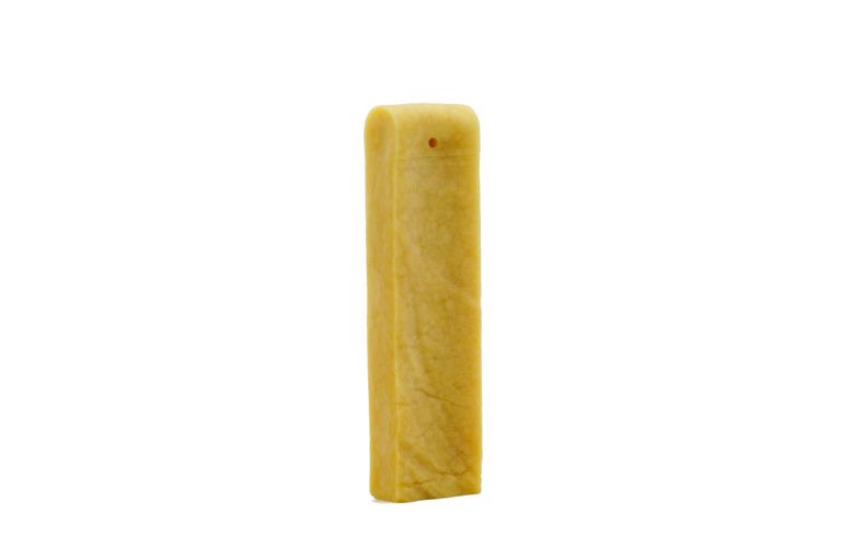 Bastoncino masticabile al formaggio, giallo, allungato. Sfondo bianco.