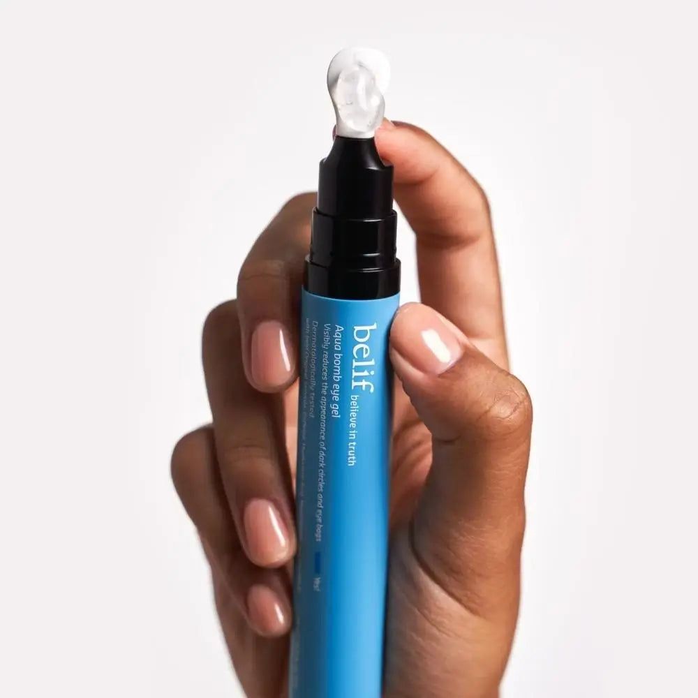 Mano che tiene l'applicatore Belif Aqua Bomb Eye Gel con applicatore in gel bianco.