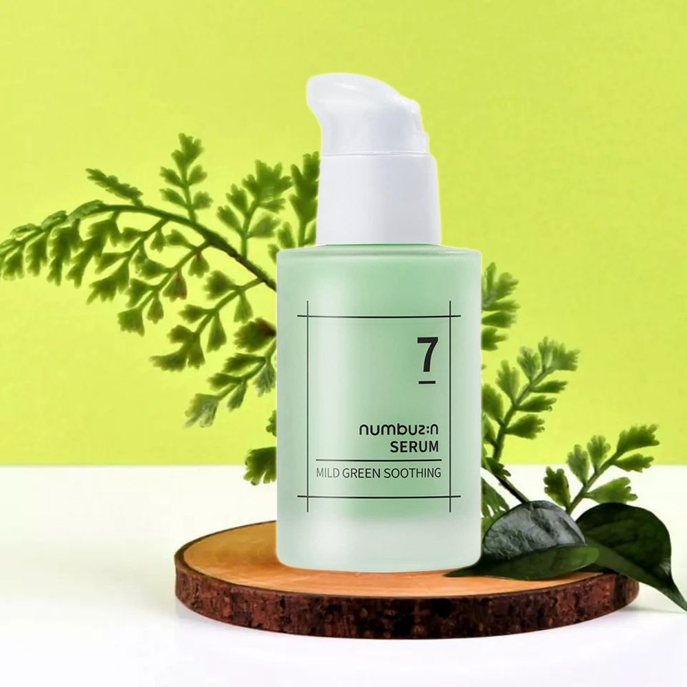 Flacone di siero verde con erogatore bianco su ceppo di legno. Scritte: 7, numbuz:n SERUM, MILD GREEN SOOTHING. Decorazione con foglie.