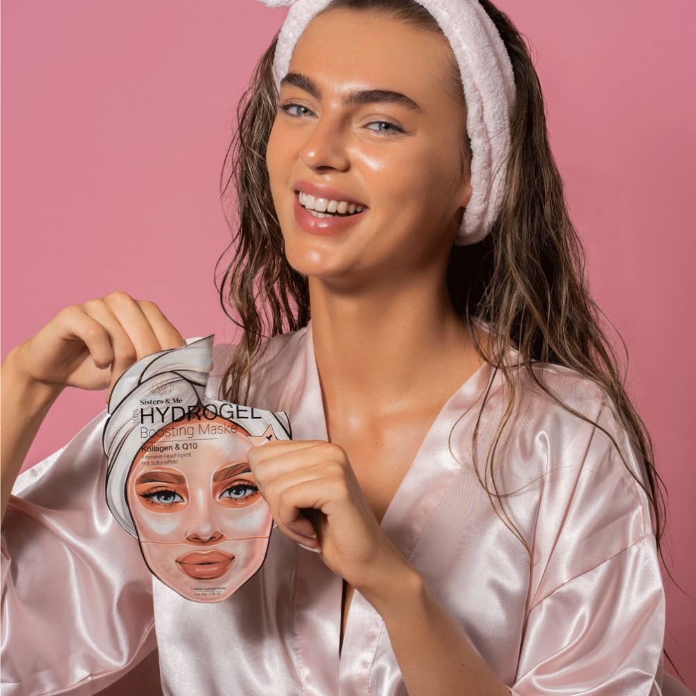 Donna tiene confezione maschera. Sulla confezione: "Sisters & Me Hydrogel Boosting Maske".