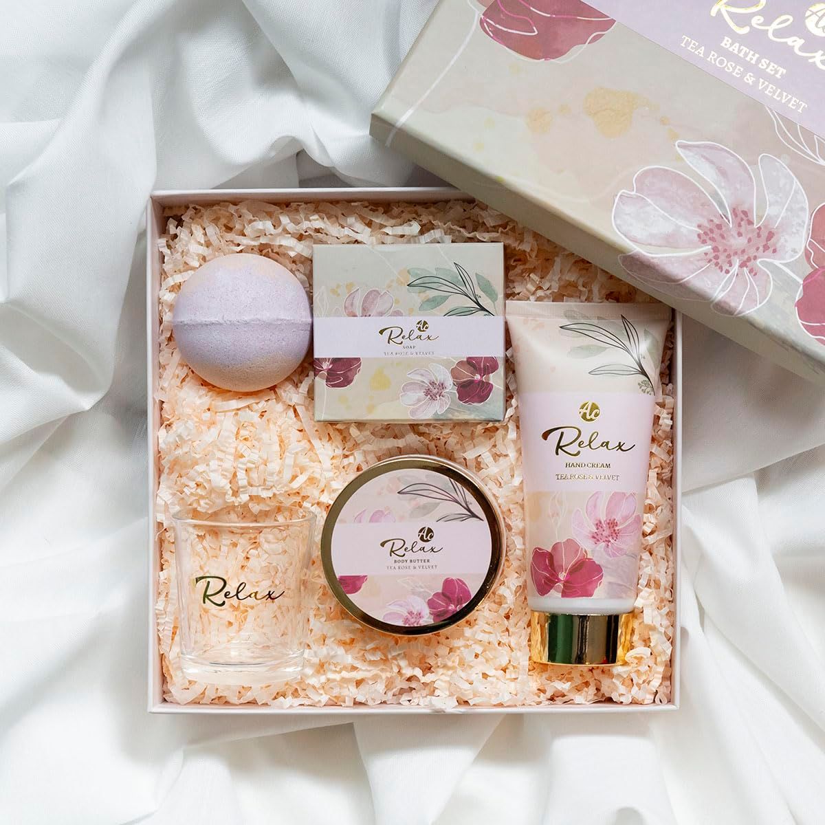 Confezione regalo con prodotti per bagno e cura della persona. Contiene crema mani, bicchiere, bomba da bagno, sapone e crema. Accenti rosa e oro.