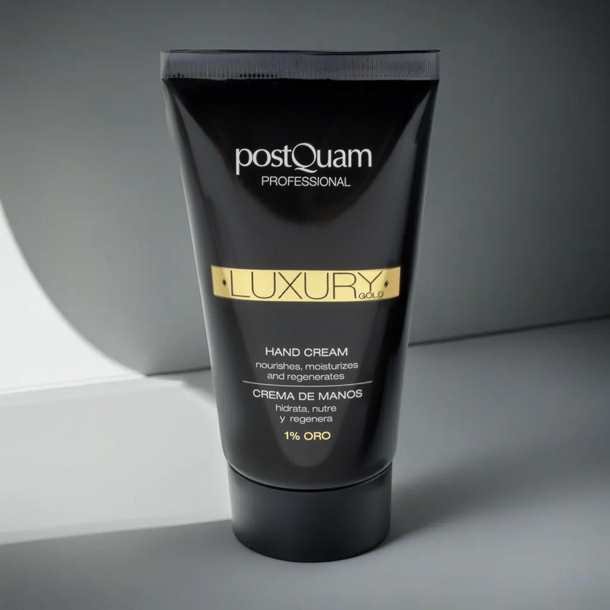 Tubo nero di crema mani con scritta dorata "LUXURY" e "1% ORO". Marchio: Postquam Professional. Testo: Hand Cream, Creme de Manos.