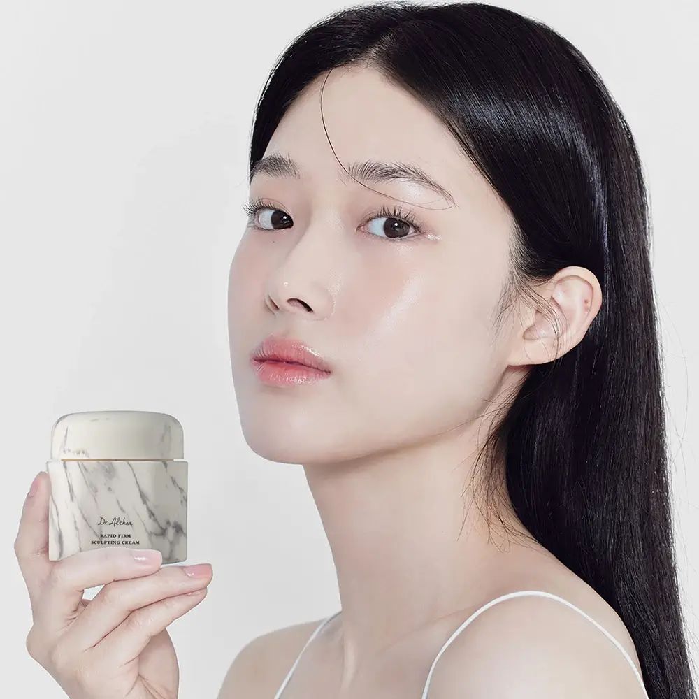 Donna tiene un vaso di crema con motivo marmorizzato. Scritta: Dr. Althea, Rapid Firm Sculpting Cream.
