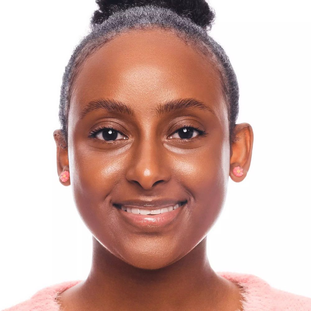 Ritratto di una donna con la pelle abbronzata. Indossa orecchini rosa e un maglione rosa. I suoi capelli sono raccolti.