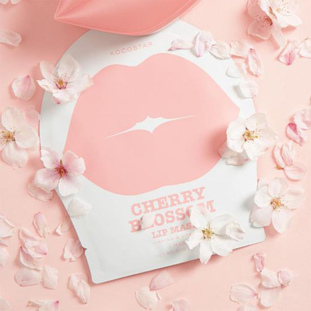 Confezione maschera labbra circondata da petali e fiori. Sfondo rosa. Testo: Cherry Blossom Lip Mask. Marchio: KOCOSTAR.