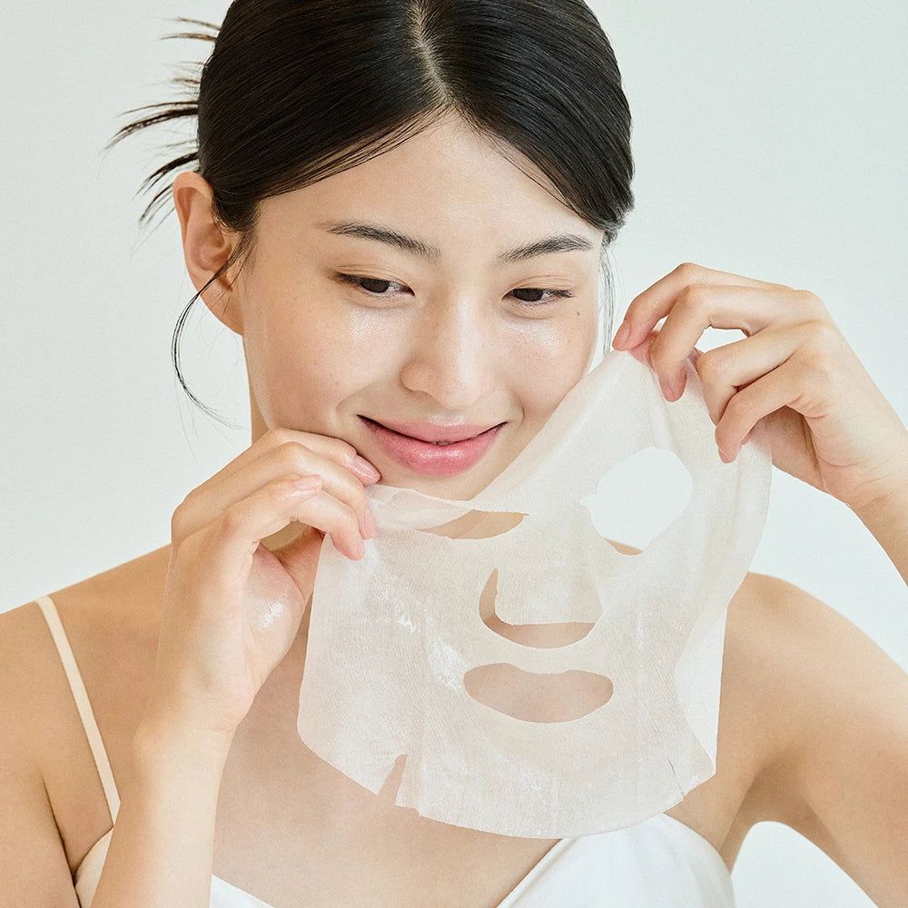 Donna che tiene una maschera per il viso. Maschera con aperture per occhi, naso e bocca. La donna sorride.