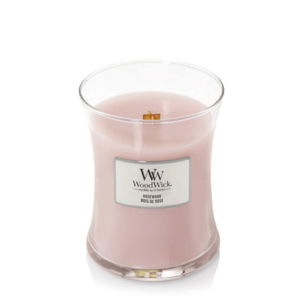 Candela a clessidra con stoppino in legno. Cera rosa, etichetta con logo e testo. Contenitore in vetro trasparente. Stoppino in legno visibile.
