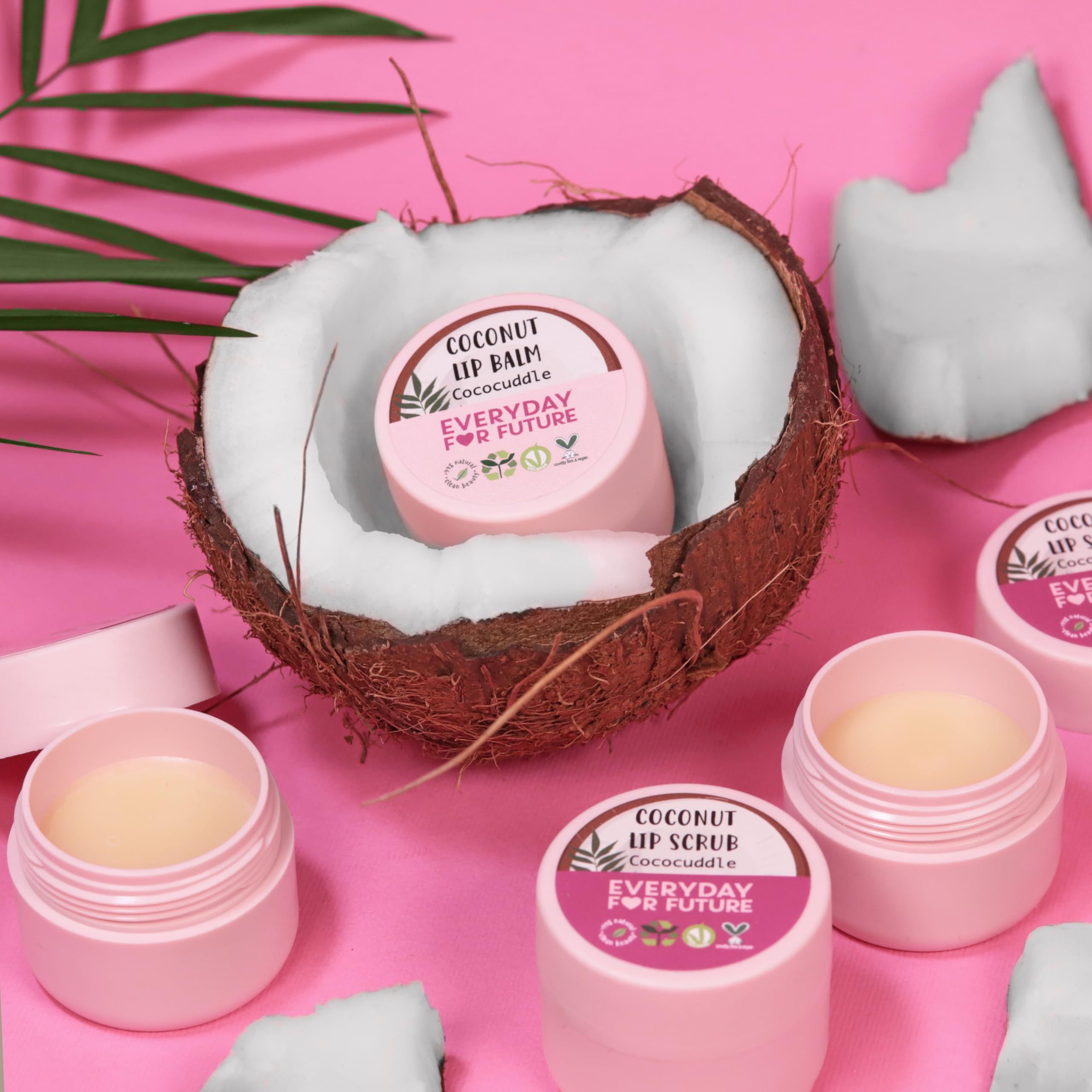 Diversi vasetti rosa di scrub e balsamo labbra, posizionati dentro e intorno a una noce di cocco. Scritta: Everyday For Future.