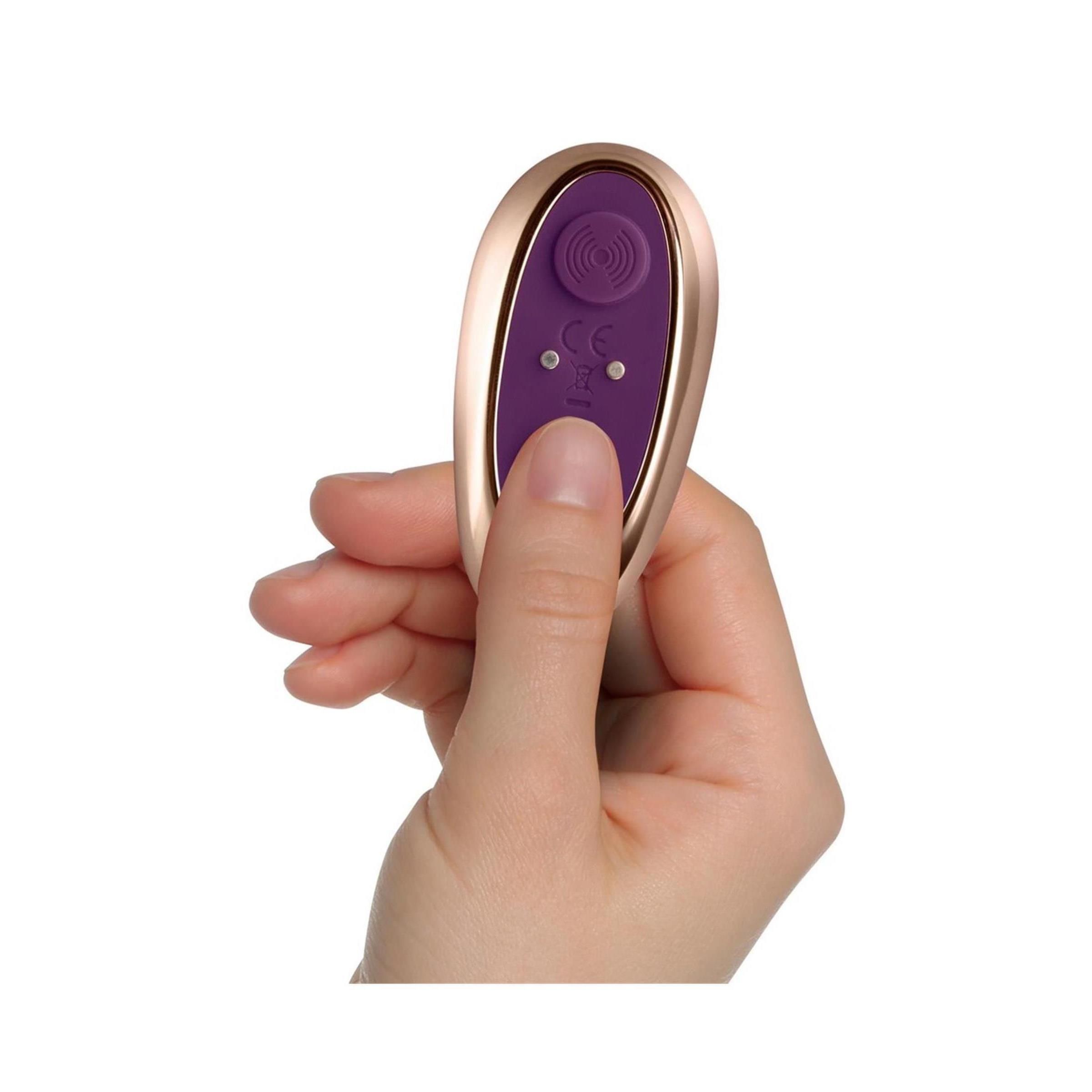 Mano che tiene un telecomando dorato. Pulsanti viola. Marchio CE.