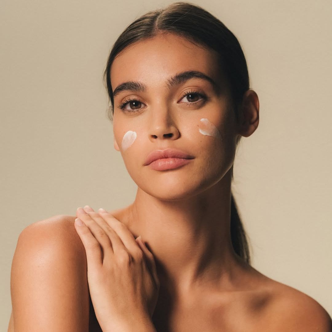 Una donna con due macchie di crema sulle guance.