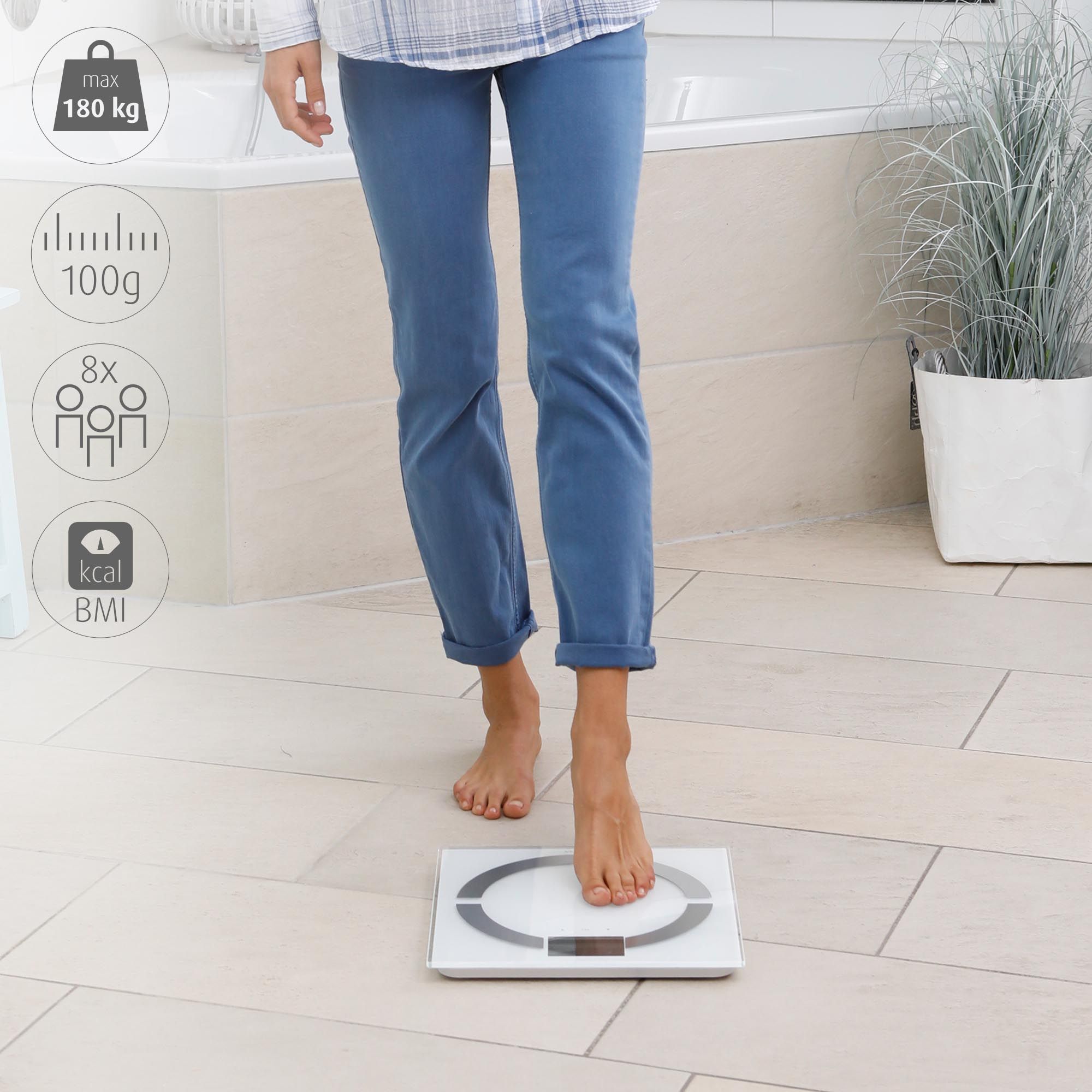 Persona in piedi su bilancia analisi corporea bianca. Display digitale. Carico massimo 180 kg. Simboli BMI e kcal.